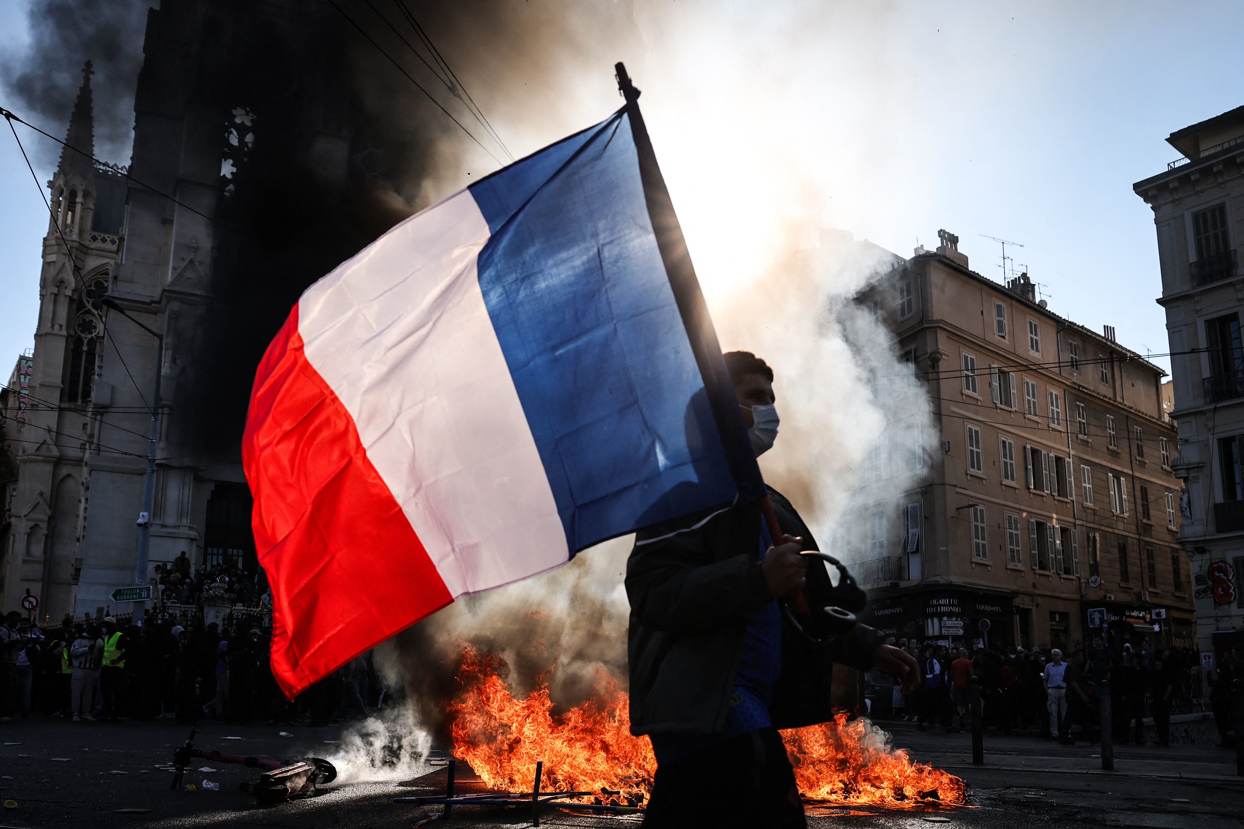 A protester waves the French flag near a fire during clashes over rising living costs in Marseille, France, on October 17. (AFP Image)