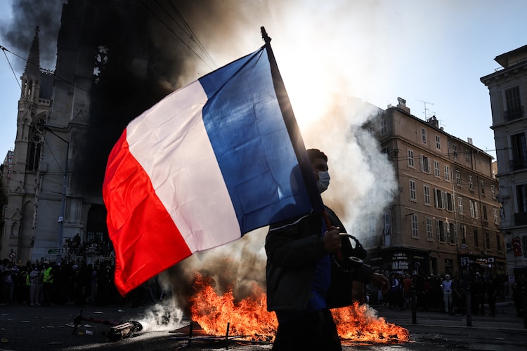A protester waves the French flag near a fire during clashes over rising living costs in Marseille, France, on October 17. (AFP Image)