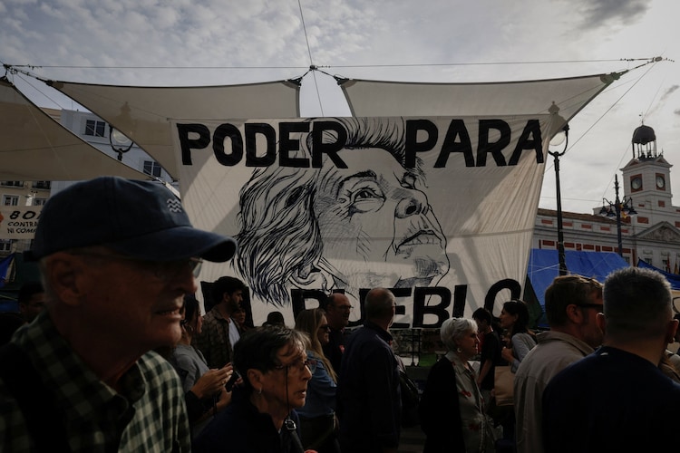People walk past a banner depicting Maricarmen Abascal, whose eviction sparked housing protests, at Madrid's Puerta del Sol on October 17. (Image: Reuters)