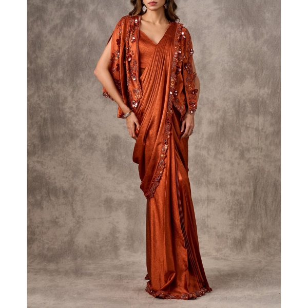 https://akm-img-a-in.tosshub.com/lingo/brt/images/photo_gallery/202606/twamev_orange_satin_sequin_floral_applique_mirror_work_cape_draped_saree_rs41999.png