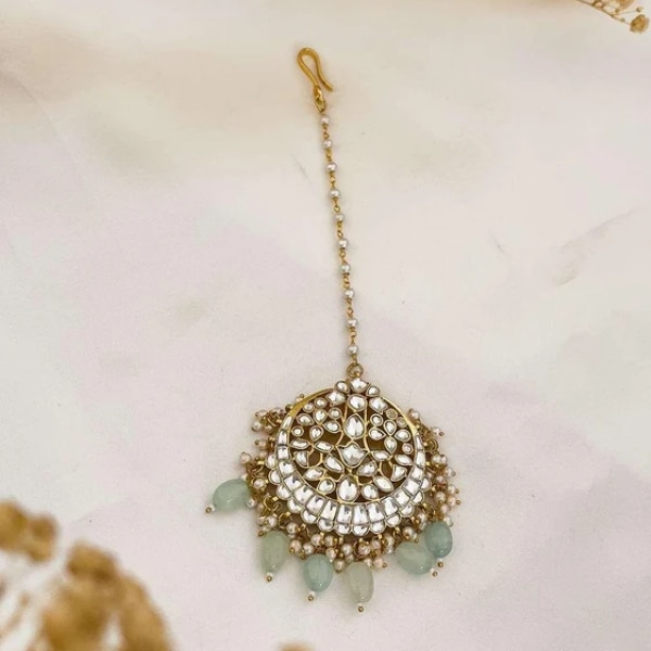 https://akm-img-a-in.tosshub.com/lingo/brt/images/photo_gallery/202607/ishhaara_gold_finish_kundan_polki_maang_tikka_rs7500.png