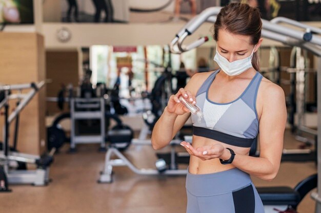 woman-with-medical-mask-gym-using-hand-sanitizer_23-2148762616.jpg