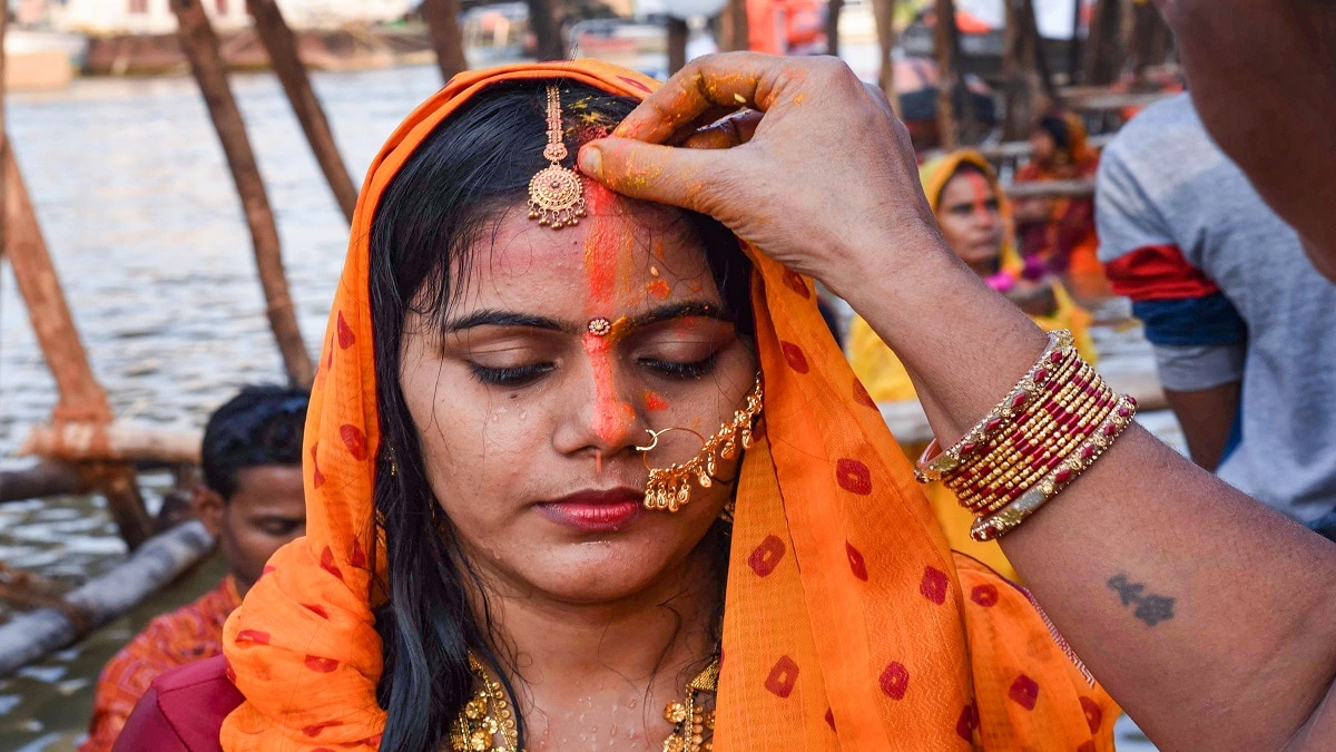 अर्घ्य देने के बाद एक दूसरे को सिंदूर लगाती व्रती.