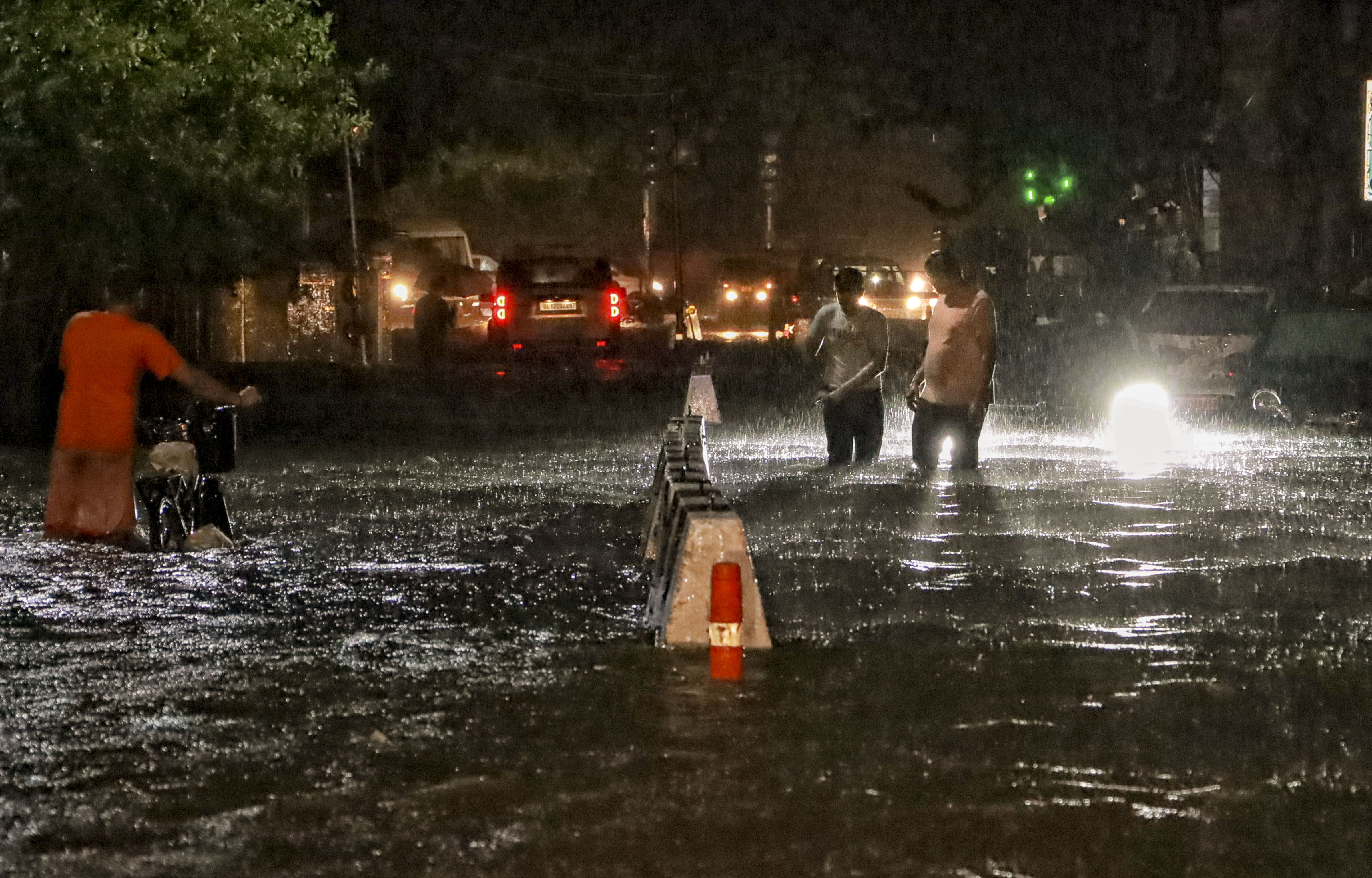 People wade through a waterlogged road during rain at Jangpura area (PTI Photo)