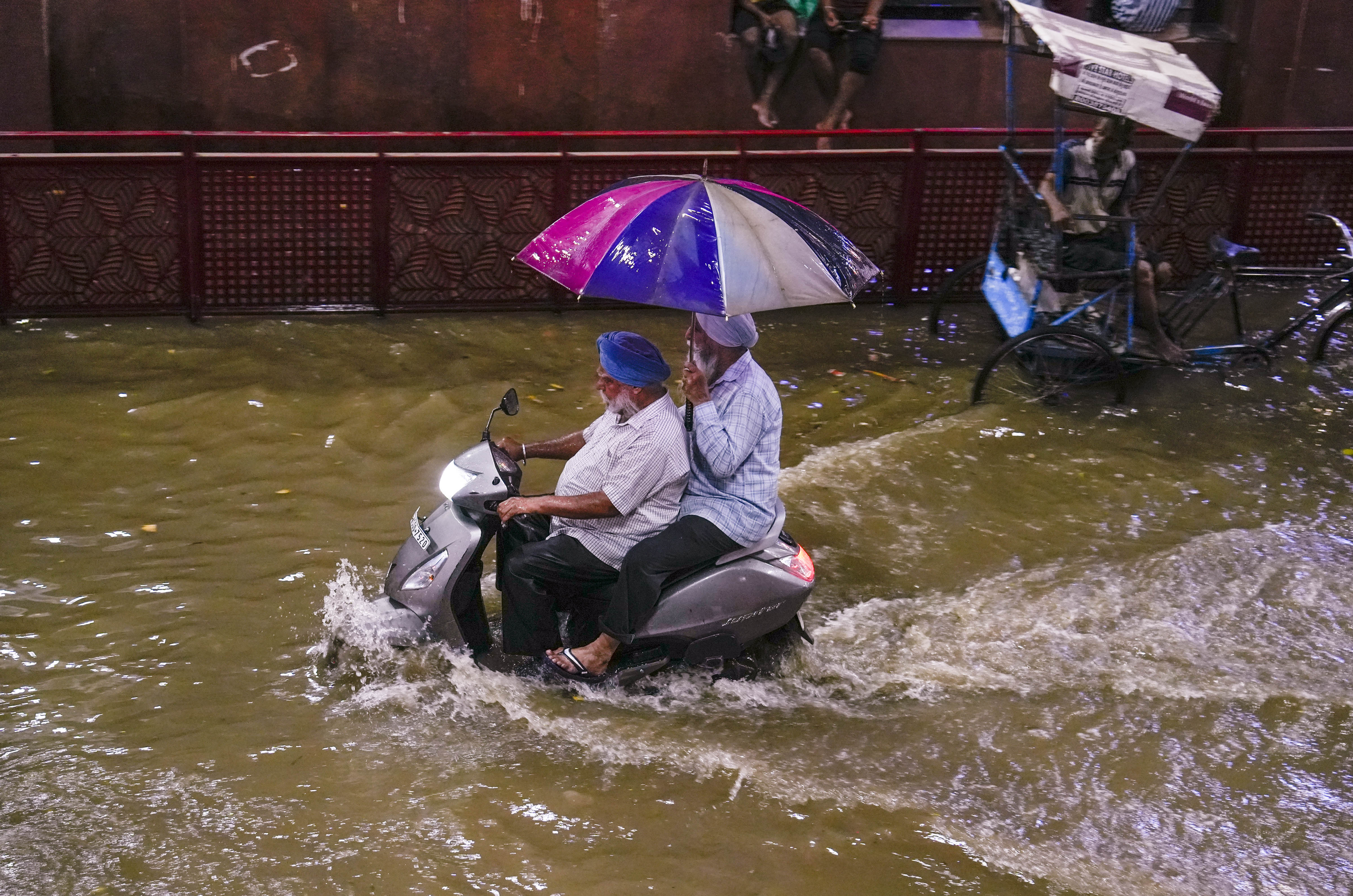 People wade through a waterlogged road at Karol Bagh metro station (PTI Photo)