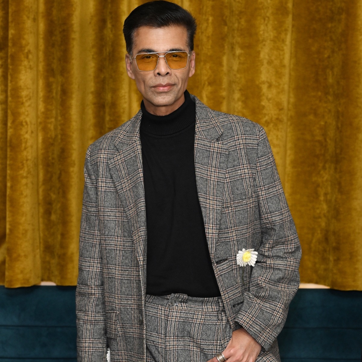 Karan Johar makes a case fot menswear with a daisy-embellished plaid suit and sunshine-tinted shades