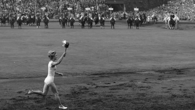 मेलबर्न ओलंपिक-1956 के दौरान हाथ में मशाल लिए दौड़ती एक महिला/IOC मेलबर्न ओलंपिक-1956 के दौरान हाथ में मशाल लिए दौड़ती एक महिला/IOC
