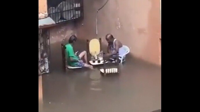 a pair of uncles drinking alcohol while sitting on a table and chair in floodwaters video goes viral mumbai rain