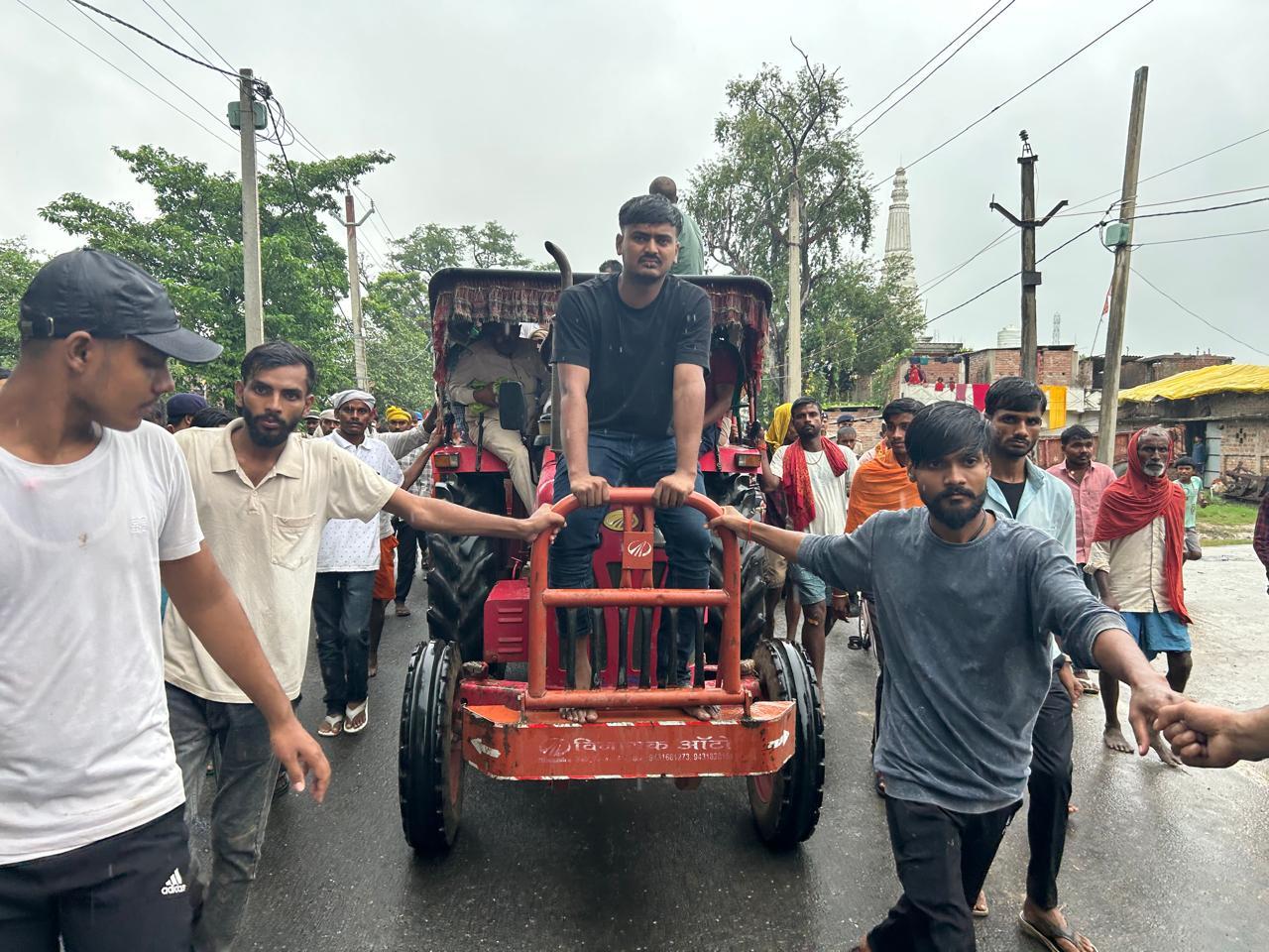 दुलार चंद यादव के शव को ले जा रहा ट्रैक्टर और उसके आगे बैठा उनका पोता