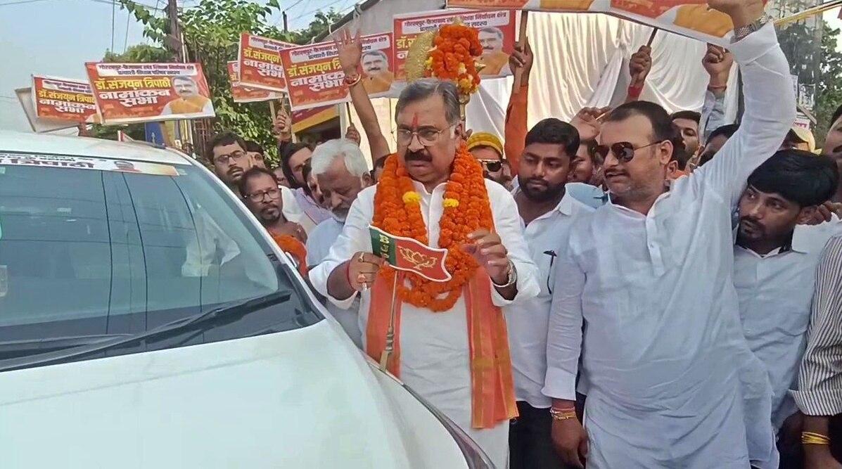 अपनी कार से BJP का झंडा उतारते संजयन त्रिपाठी
