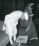 Nehru peers at <em>The Times of India</em> with Indira Gandhi at his side