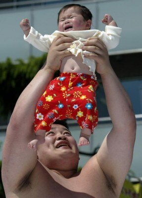 A baby breaks into tears in the arms of an amateur sumo wrestler during a baby crying contest at Sensoji temple in downtown Tokyo April 29, 2004. Seventy babies born in 2003 participated in the event which is held to wish for the babies's [health] and growth. The loudest crying baby will be the winner in the event, which is held in many towns all over Japan.