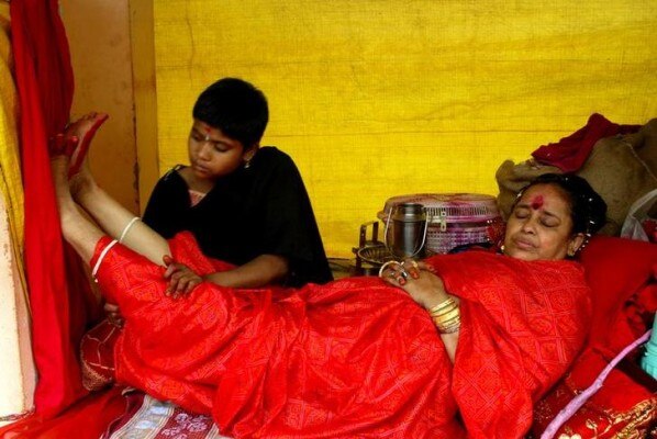 An Indian girl massage leg of a Hindu woman priest at the Kamakhya Temple in the northeastern Indian city of Guwahati June 22, 2003. Seers and pilgrims are arriving at the temple, which is famous for the teaching of black magic known traditionally as 'Tantra', for the annual four day 'Ambubachi Mela', which starts on June 22 when pilgrims and Seers believe their prayers will be answered during the festival. Pictures of the month June 2003. PP03060064 REUTERS/Jayanta Shaw JS/CP
