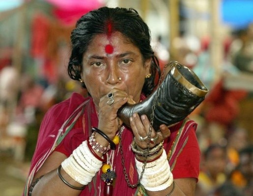 An Indian Hindu woman priest plays an instrument made from buffalo horn at the Kamakhya Temple in the northeastern Indian city of Guwahati June 22, 2003. Seers and pilgrims are arriving at the temple, which is famous for the teaching of black magic known traditionally as 'Tantra', for the annual four day 'Ambubachi Mela', which starts on June 22 when pilgrims and Seers believe their prayers will be answered during the festival.
