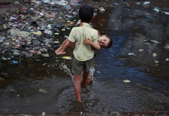 Ashfaq, 10, carries his two-year-old brother Farhaan through a flooded pathway in a Mumbai slum June 6, 2011. REUTERS/Danish Siddiqui (INDIA - Tags: SOCIETY IMAGES OF THE DAY)