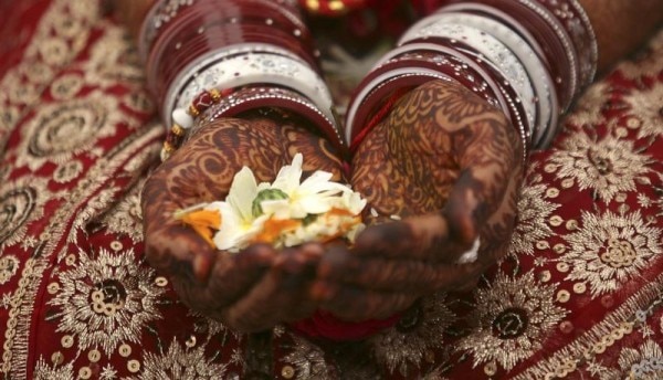 A bride holds flowers with her hands decorated with henna paste during her wedding ceremony in the western Indian city of Ahmedabad January 22, 2012. Seven blind couples tied the knot in a traditional Hindu marriage ceremony in western India on Sunday, arranged by a voluntary organisation, organisers said. REUTERS/Amit Dave (INDIA - Tags: SOCIETY) - RTR2WO5A