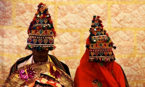 A bride and groom wearing traditional handmade garlands wait for their wedding to start during a mass marriage ceremony in Karachi, Pakistan, January 24, 2016. The Pakistan Hindu Council organized a mass marriage ceremony where a total of 60 couples from the Hindu community residing in Pakistan's Sindh province took wedding vows, according to the council. REUTERS/Akhtar Soomro