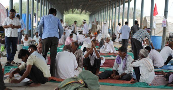 सीकर सब्जी मंडी में समूह में बैठे किसान, पास में आटा गूंथा जा रहा है