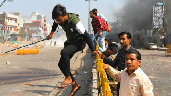 इस तस्वीर में एक गुट के लोग रोड के डिवाइडर को कूदकर पार करते हुए. क्रेडिट- रॉयटर्स. Caa Protest 9