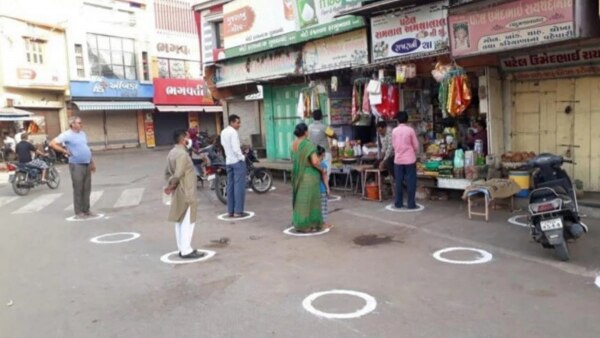 सोशल डिस्टेंसिंग का बेहतरीन नमूना. गुजरात की एक दुकान में लोग अपनी तय जगह पर खड़े होकर राशन खरीदते हुए. (क्रेडिट: ट्विटर/किरण बेदी) Social Distancing