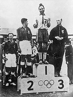 1956 के मेलबर्न ओलंपिक विक्ट्री सेरेमनी में बीच में खड़े कप्तान बलबीर सिंह सीनियर. फोटो: विकीमीडिया 1956 के मेलबर्न ओलंपिक विक्ट्री सेरेमनी में बीच में खड़े कप्तान बलबीर सिंह सीनियर. फोटो: विकीमीडिया