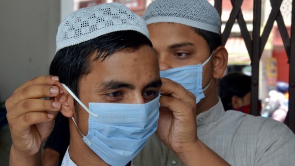 अमृतसर में एक दोस्त को मास्क पहनाता व्यक्ति. (फोटो- PTI) Coronavirus Infection (1)