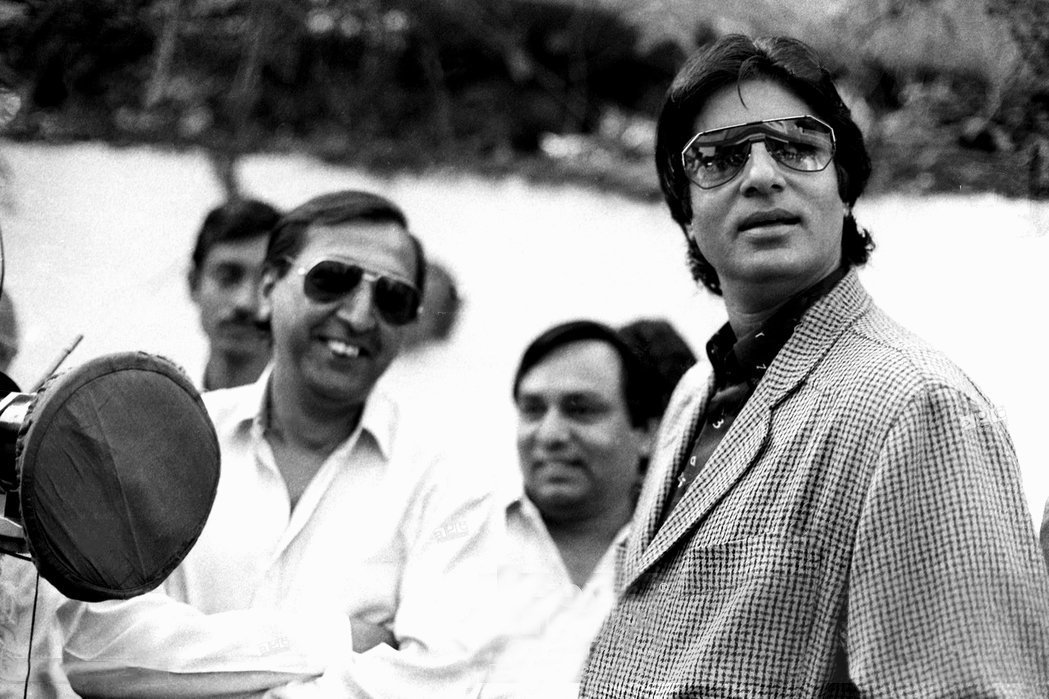 एक फिल्म के सेट पर अमिताभ बच्चन और नेपथ्य चश्मा लगाए टिनू आनंद. एक फिल्म के सेट पर अमिताभ बच्चन और नेपथ्य चश्मा लगाए टिनू आनंद.
