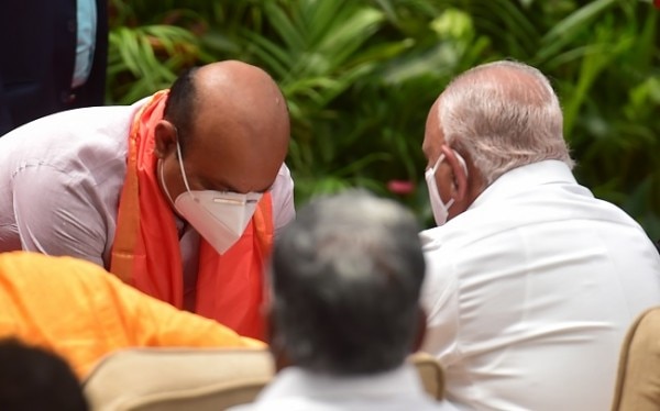 शपथ लेने से पहले येदियुरप्पा के पैर छूते कर्नाटक के नए सीएम बसवराज बोम्मई. (तस्वीर- पीटीआई) Basavaraj