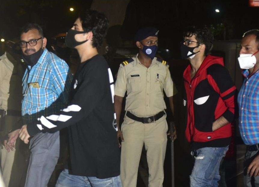 गिरफ्तारी के बाद NCB के अफसरों के साथ जाते आर्यन खान और उनके दोस्त अरबाज़ मर्चेंट (लाल जैकेट में). गिरफ्तारी के बाद NCB के अफसरों के साथ जाते आर्यन खान और उनके दोस्त अरबाज़ मर्चेंट (लाल जैकेट में).