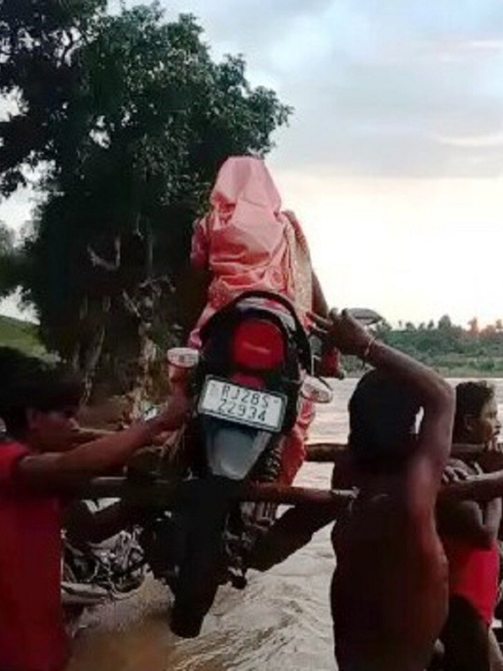 उफनती नदी में कंधों पर बाइक और बाइक पर महिला...