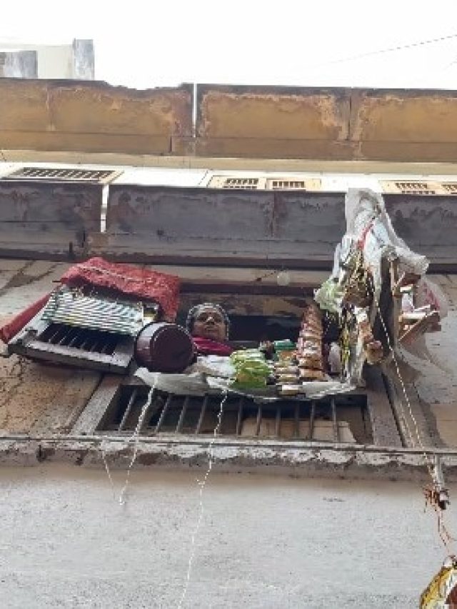 तंग गलियां, भीड़ में स्मार्ट आइडिया. बनारस में खिड़की से चल रही पूजा-सामान की दुकान